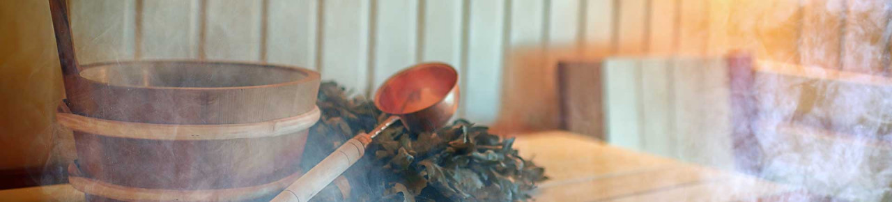 Inneres einer beheizten Sauna mit Wasserdampf in der Luft; zudem präparierte Utensilien für einen Saunaaufguss